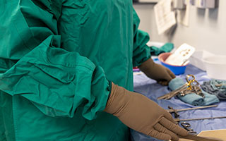 A close-up shot of a hospital employee wearing a green reusable surgical gown in an operating room at the General Campus.